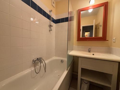 une salle de bain avec une baignoire, un lavabo et un miroir dans l'établissement Appartement 2 chambres avec piscines chauffées et parking aux Sables-d'Olonne - FR-1-197-615, à Les Sables-dʼOlonne