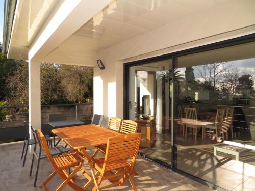 un patio avec une table et des chaises en bois dans l'établissement Villa moderne 5 pièces avec WIFI, climatisation, et parkings à Sète - FR-1-338-597, à Sète