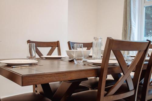 a wooden table with chairs and plates and glasses on it at Spacious 13-Bed in the Heart of Headingley in Headingley
