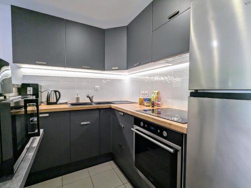 une cuisine avec des armoires noires et un réfrigérateur en acier inoxydable dans l'établissement Spacieux appartement 3 chambres, proche ski et nature, WiFi, parking, animaux admis - FR-1-589-782, à Cornimont