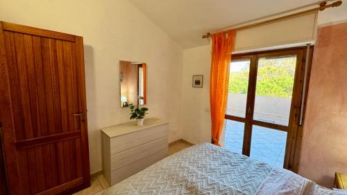 a bedroom with a bed and a dresser and a window at Appartamento Quadrifoglio in Castelsardo