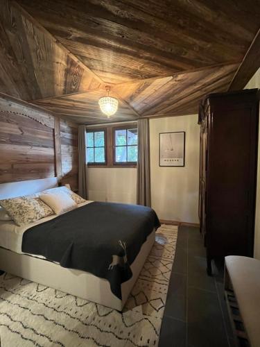 une chambre avec un lit et un plafond en bois dans l'établissement Confort et Proximité, à Megève