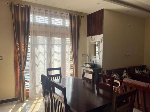 a dining room with a table and chairs and a window at Western Royal Homes in Bengaluru