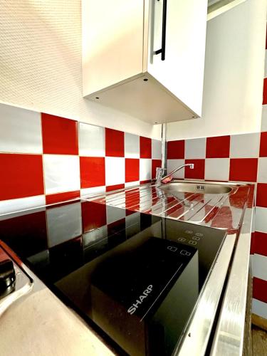 - une cuisine avec un mur en damier rouge et blanc dans l'établissement La Dépendance - studio cosy, à Rouen