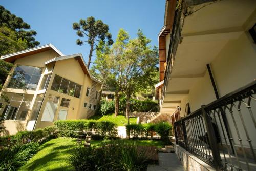 a building with a fence next to a yard at Araucária Lodge - 800 metros do Capivari in Campos do Jordão