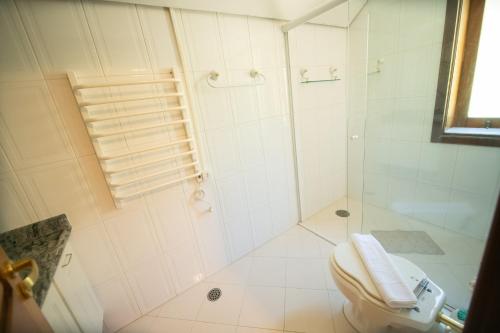 a white bathroom with a shower and a toilet at Araucária Lodge - 800 metros do Capivari in Campos do Jordão