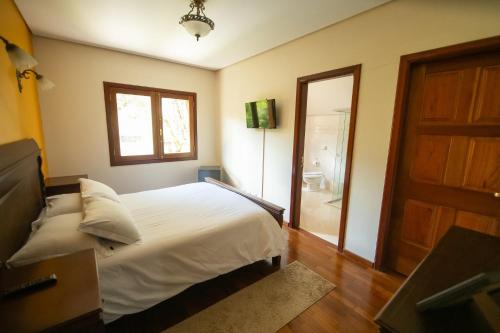 a bedroom with a bed and a window and a door at Araucária Lodge - 800 metros do Capivari in Campos do Jordão
