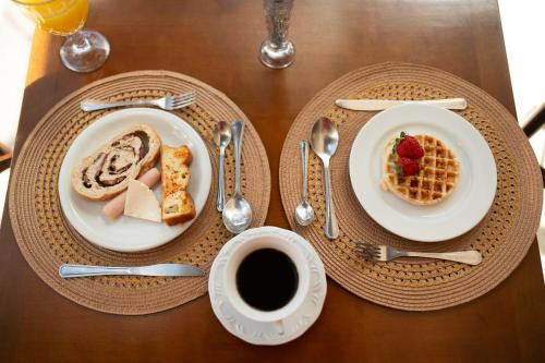 a table with two plates of food and a cup of coffee at Araucária Lodge - 800 metros do Capivari in Campos do Jordão