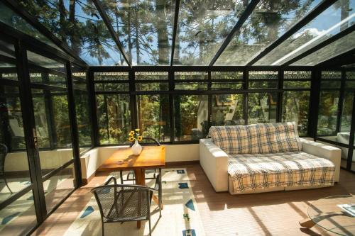a room with a conservatory with a couch and a table at Araucária Lodge - 800 metros do Capivari in Campos do Jordão