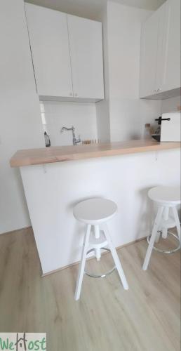 - une cuisine blanche avec deux tabourets et un évier dans l'établissement Paroisse - CI - Versailles Le Cocon, nid douillet à deux pas du Château, à Versailles