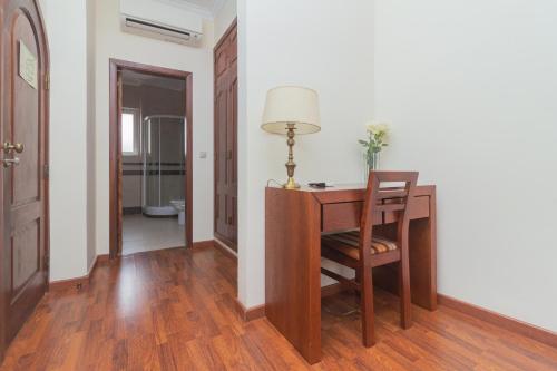 a room with a desk and a table with a lamp at Hospedaria Maioral in Vila Franca de Xira