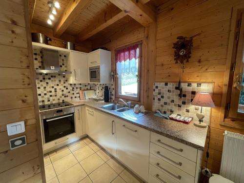 une cuisine avec des armoires blanches, un évier et une fenêtre dans l'établissement Chalet familial avec Wifi et parking aux Gets - FR-1-671-280, aux Gets
