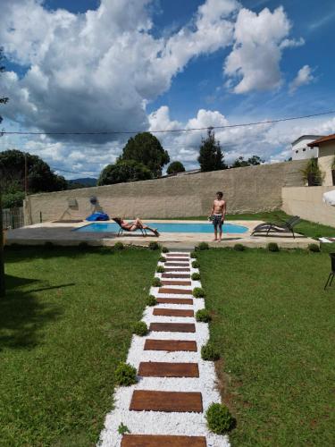 a man standing next to a swimming pool at Pousada Flores do Campo in Águas de Lindóia