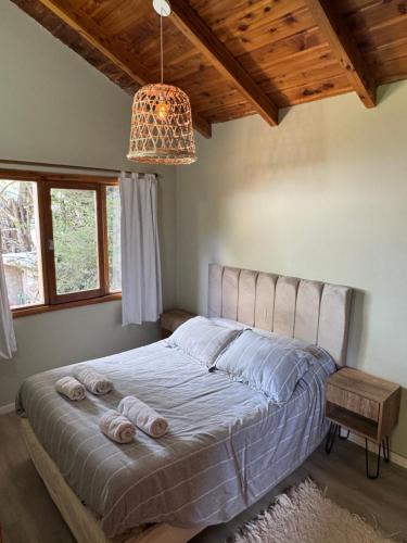 a bedroom with a large bed with a chandelier at Casa a metros del lago Gutiérrez in San Carlos de Bariloche