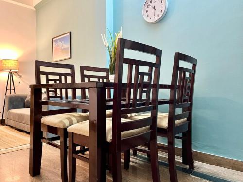 a dining room table with chairs and a clock on the wall at Luxury 2BHK Apartment in Bengaluru- GF in Bengaluru