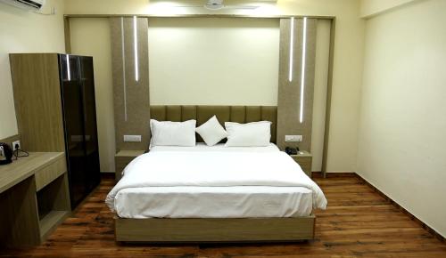 a bedroom with a large bed with white sheets and pillows at Hotel Royal Bistro in Mehsāna