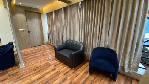 a living room with a black chair and a blue chair at Hotel Royal Bistro in Mehsāna