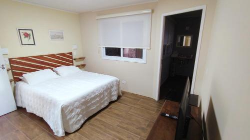 a bedroom with a white bed and a television at Araucária Lodge - 800 metros do Capivari in Campos do Jordão