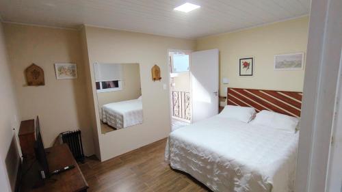 a small bedroom with a bed and a mirror at Araucária Lodge - 800 metros do Capivari in Campos do Jordão