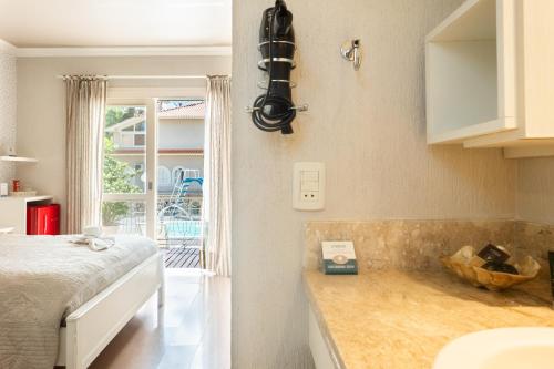 a bedroom with a bed and a sink and a window at Doce Canela - Pousada de Charme in Canela