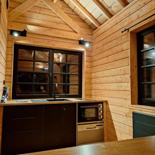 - une cuisine dotée de murs en bois et d'un four avec plaques de cuisson dans l'établissement Chalet charmant à Cons-la-Grandville 50 m² avec jardin, à Cons-la-Grandville