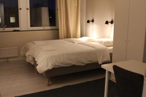 a bedroom with a bed with white sheets and a window at Hotell Bromma in Stockholm