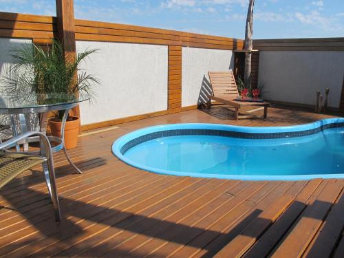 a deck with a swimming pool and a table at Hotel Bonnel Eirelli - Tropical in Cachoeira do Sul