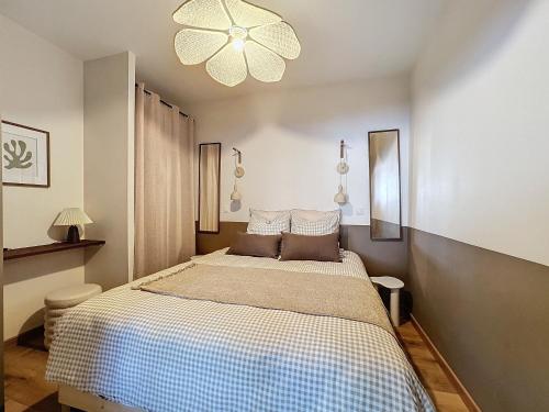 a bedroom with a bed and a chandelier at Le pétillant champenois in Reims