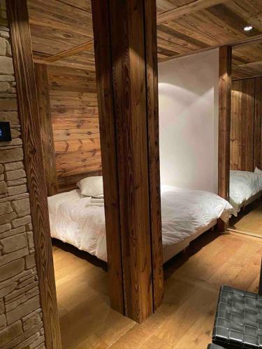 deux lits jumeaux dans une chambre aux murs en bois dans l'établissement Appartement 1er Coeur de megeve, à Megève