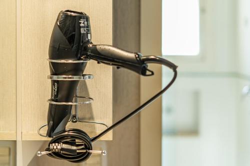 a black hair dryer hanging on a wall at Doce Canela - Pousada de Charme in Canela