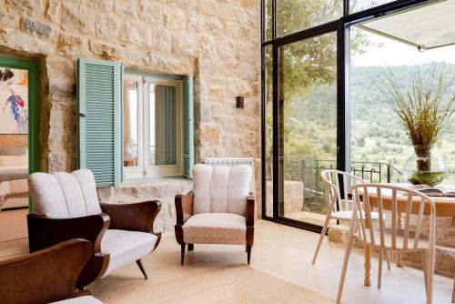 a living room with a table and chairs and windows at Casadar Guesthouse in Ash Shi‘b