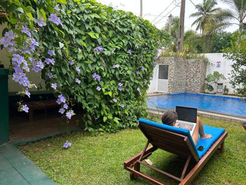 a woman sitting in a lawn chair with a laptop at Kurulu Villa Hikkaduwa in Gonapinuwala West