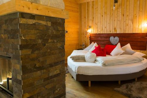 a bed in a room with a brick fireplace at Domaine du Haut Jardin Hôtel & Chalets Spa Privé in Rehaupal