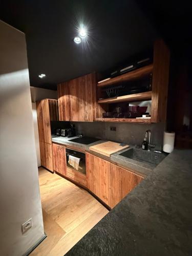 une cuisine avec des armoires en bois et un four à plaques de cuisson dans l'établissement Apartement RDJ CŒUR DE MEGEVE, à Megève