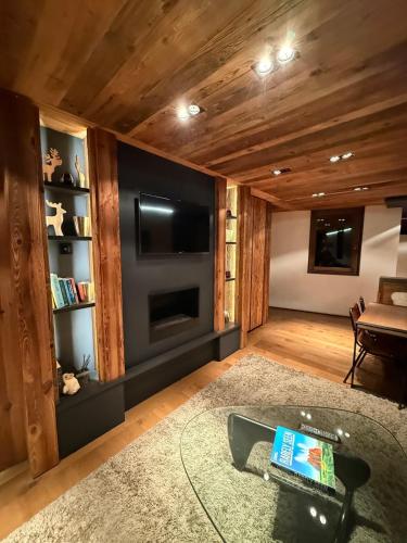 - un salon avec une grande télévision et un canapé dans l'établissement Apartement RDJ CŒUR DE MEGEVE, à Megève