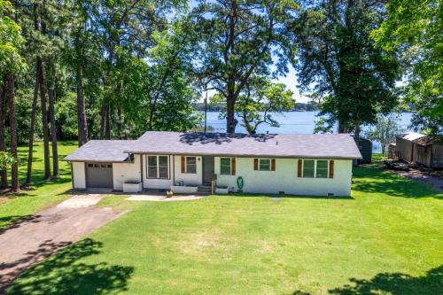 a small white house with a large yard at Lakefront Daingerfield Retreat with Shared Dock! in Daingerfield