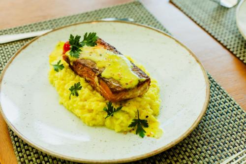 a plate of food with a piece of fish and eggs at Royal Golden Hotel - Savassi in Belo Horizonte