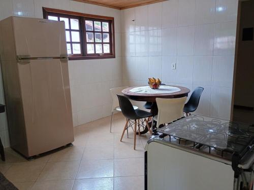 a kitchen with a small table and a refrigerator at Casa Campobello - centro de Miguel Pereira in Miguel Pereira