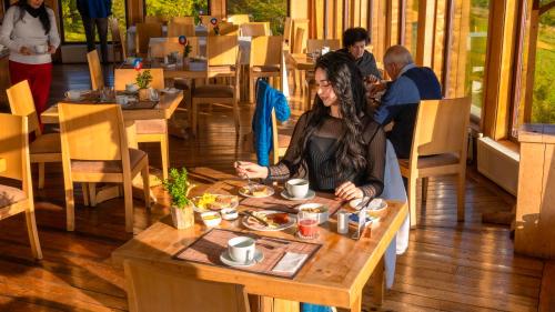 a woman sitting at a table in a restaurant at Hotel Parque Quilquico in Castro