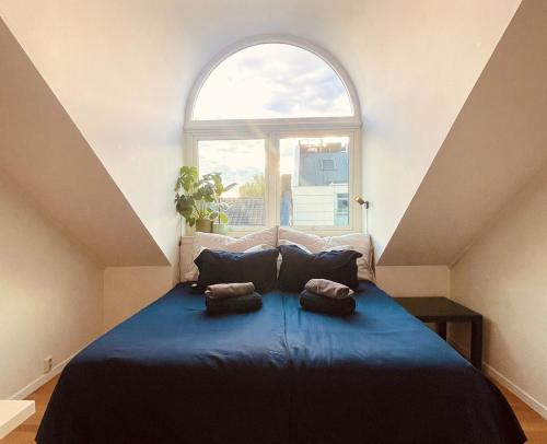 a bedroom with a blue bed with a window at Penthouse apartment balcony,parking and 2 bedrooms in Oslo