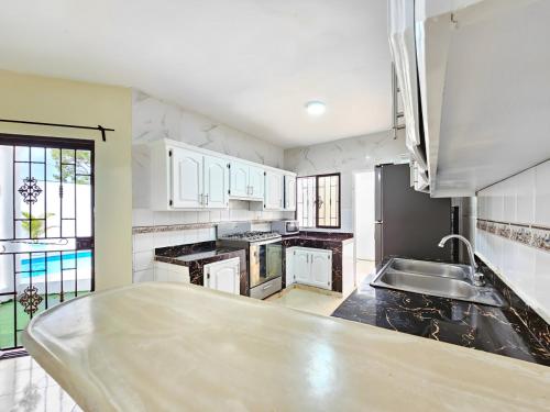 a large kitchen with white cabinets and a sink at Villa DMM con piscina, jacuzzi y gran área verde en Punta Cana in Punta Cana
