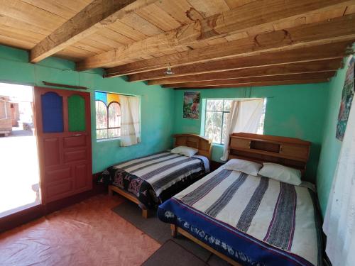 2 letti in una camera con pareti verdi di Home in Taquile - Q'uñi wasi a Huillanopampa