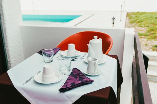 a table with a white table cloth and a red chair at Suíte Leonor in Alijó