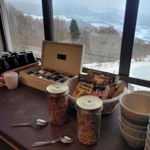 une table avec une caisse de nourriture et une fenêtre dans l'établissement Village Montanha Lioran, à Saint-Jacques-des-Blats