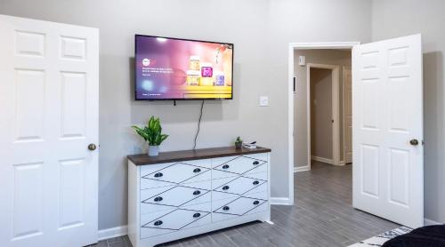 a bedroom with a dresser with a tv on a wall at 6S Hideout Houston in Cypress