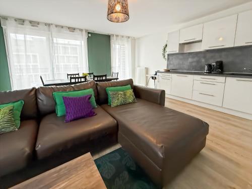 - un salon avec un canapé en cuir brun et des oreillers colorés dans l'établissement Suite Kalista Disneyland Paris - Rentaway BnB, à Montévrain