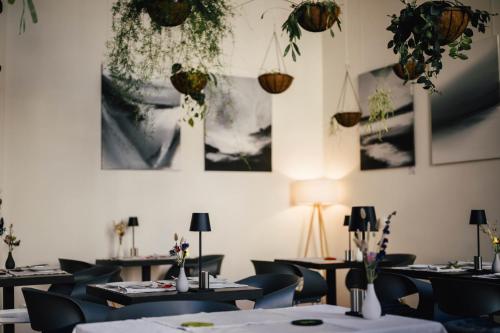 a dining room with tables and chairs and plants at The Layhead B&B in Lübeck
