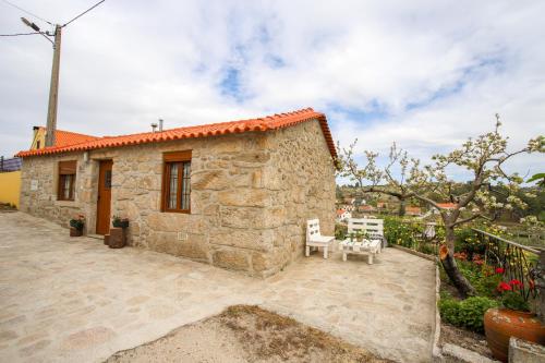 a stone house with a patio with two chairs at Casa do Avô in Sortelha