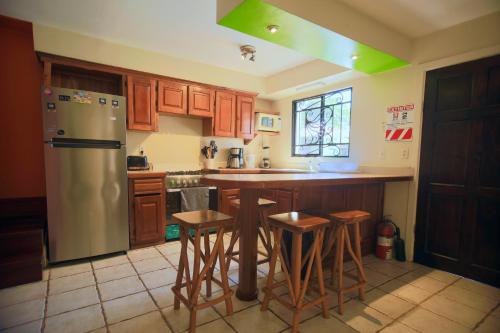 a kitchen with a stainless steel refrigerator and bar stools at Wipeout Hostel in Jacó