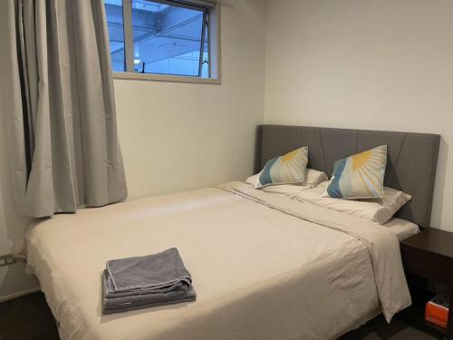 a bedroom with a large bed with a window at AURA B two bedrooms, 1 living room Wi-Fi skytower and street view, balcony , easy parking in Auckland